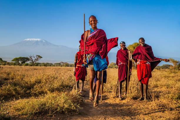 African warrior from Maasai tribe performing a traditional jumping dance, central Kenya, Africa - Mount Kilimanjaro on the background. Maasai tribe inhabiting southern Kenya and northern Tanzania, and they are related to the Samburu.